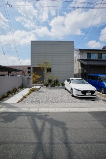 フラット屋根の建物に小窓をアクセントとし、植栽で彩ることでシンプルかつ存在感のある外観です。

植栽の間を縫うように計画したアプローチや、通りから見えない位置に玄関を配置することで邸宅感を演出しています。