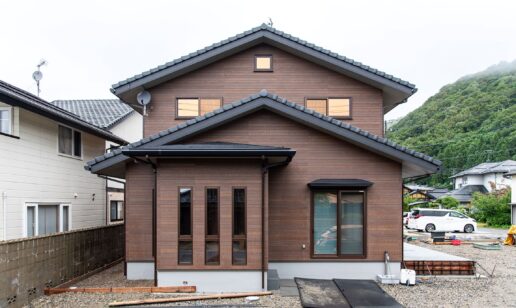 左右対称の切妻屋根が印象的な均等の取れた佇まい。木目調の外壁は、落ち着いたミディアムブラウンカラー。