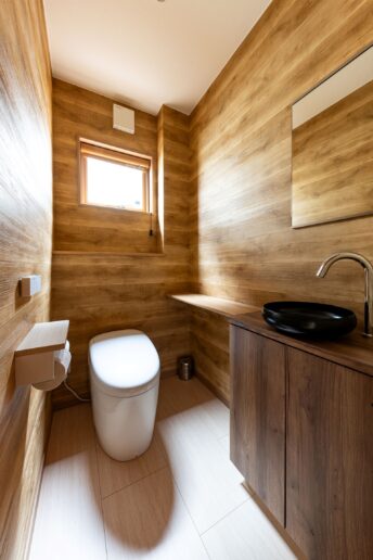 広めに作られたトイレは手洗い器とカウンター付き。木目調のクロスで仕上げられており、落ち着いた空間に。