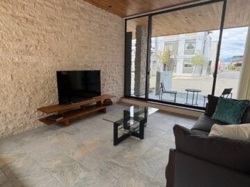 リビングは一段フロアダウンさせ、床材をタイルにしています。段差を設けることでチークのフローリングとタイルの境目に違和感がなくなっています。 TV背面の壁面にも、石貼りを施しており、全体のバランスを考えシンプルなホワイトをチョイスしています。 南北に大開口のサッシがあり、吹き抜けの効果もあり、自然な明るさと開放感のあるLDKになっています。