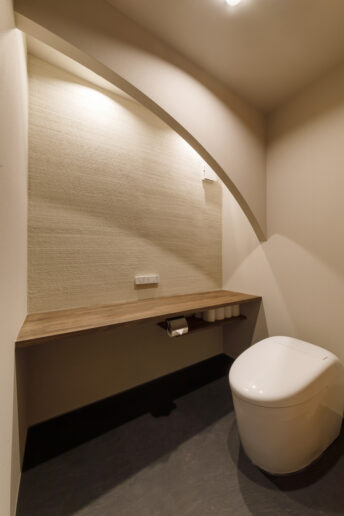 トイレは片面の壁を調湿・消臭に優れた薩摩中霧島壁に。アールの垂れ壁と間接照明がリラックス感をより高めてくれます。