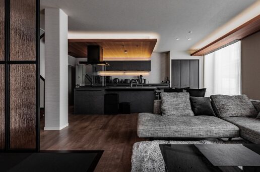 黒を基調としたキッチンに、木のぬくもりを感じる下がり天井がアクセントに。
収納棚にも間接照明を忍ばせ、調理家電がインテリアの一部のように溶け込む。