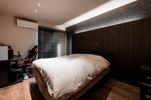 ヘッドボードに間接照明を仕込み、やわらかな光が包み込む寝室。
光の加減で表情が変わる重厚感のある壁紙を採用し、上品でモダンな印象に。