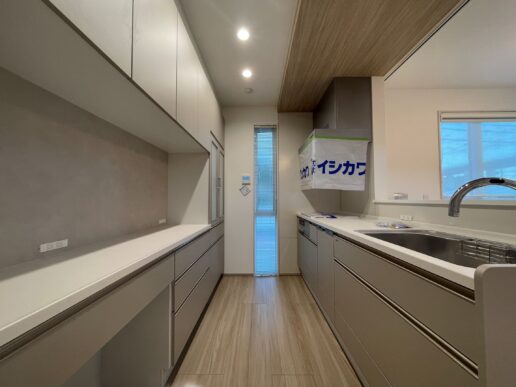 背面収納もたっぷりのキッチン。やさしい色味に、下がり天井の木目がアクセントに。