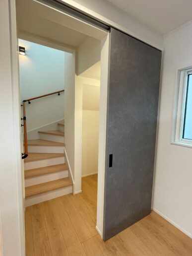 キッチンから繋がる階段スペース。必要な時は引き戸で仕切って、家族それぞれの時間も大切に。階段下は収納として無駄なく活用。