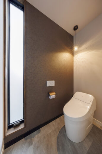 半透明のスリットガラスから柔らかな光が届く小世帯のトイレ。照明は奥様がセレクト。夜は日中とは異なる雰囲気を楽しめます。