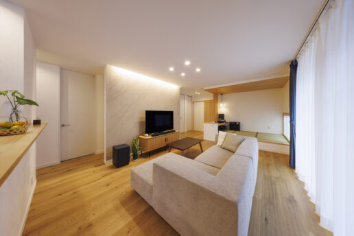 木の温もりと優しい色味が調和したLDK。テレビ背面の壁にイタリア漆喰「ユーロスタッコ」を採用。天井から注ぐ間接照明が空間を上品に演出します。