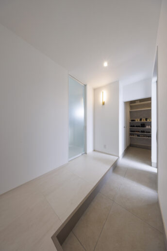 洗練された真っ白いエントランス。奥に大容量のシューズクローゼットを備え、空間をいつも美しく保つことができます。真鍮のブラケットなど、各居室の照明にもお施主様のこだわりを感じます。