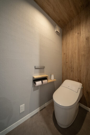 消臭・調質効果に優れた薩摩中霧島壁を施したトイレ。木目調のクロスを壁と天井にL字貼ることで縦のラインが協調され奥行きを感じられます。