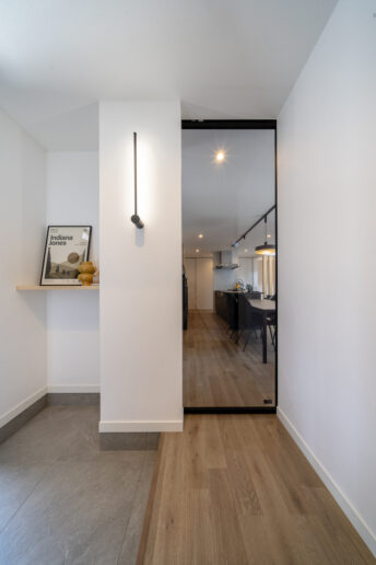 シンプルで洗練された玄関ホール。天井まで届く透明のリビングドアに視線が抜けて、より開放感が生まれました。ポール型の照明がアクセントになっています。
