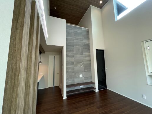 縦に広がる吹抜け空間に、エコカラットの壁面が映えるリビング。高窓からの光が壁面の質感を引き立て、空間に奥行きと上質さをプラスしています。