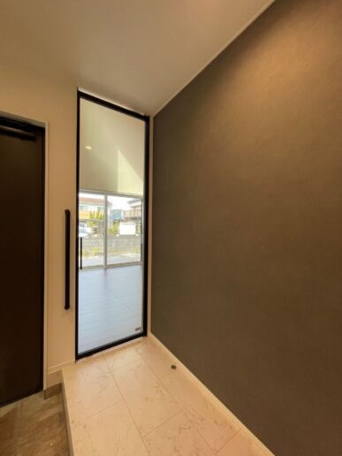 玄関からリビングへと繋がるアルミガラスのハイドアは、視線と光が抜けることで、空間の広がりを引き立てます。