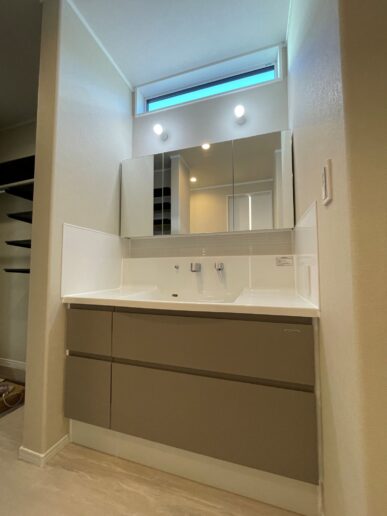 キッチンと同じやさしいグレージュの洗面は、幅1200㎜で朝の渋滞も回避。高窓から優しい自然光が入ります。