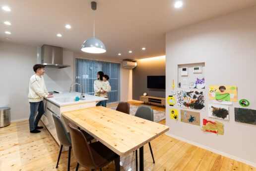 檜の床材を使ったダイニングテーブルは、ご主人がDIYしたもの。ダイニング側の壁は、お子様の作品の展示コーナーに。