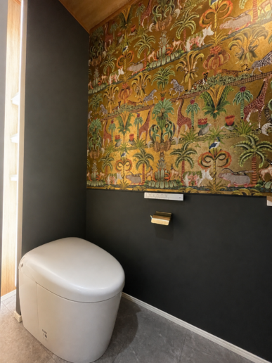 ご支給いただいた素敵なアクセントクロスが空間の主役。トイレの後ろに収納棚を設け、スッキリと。