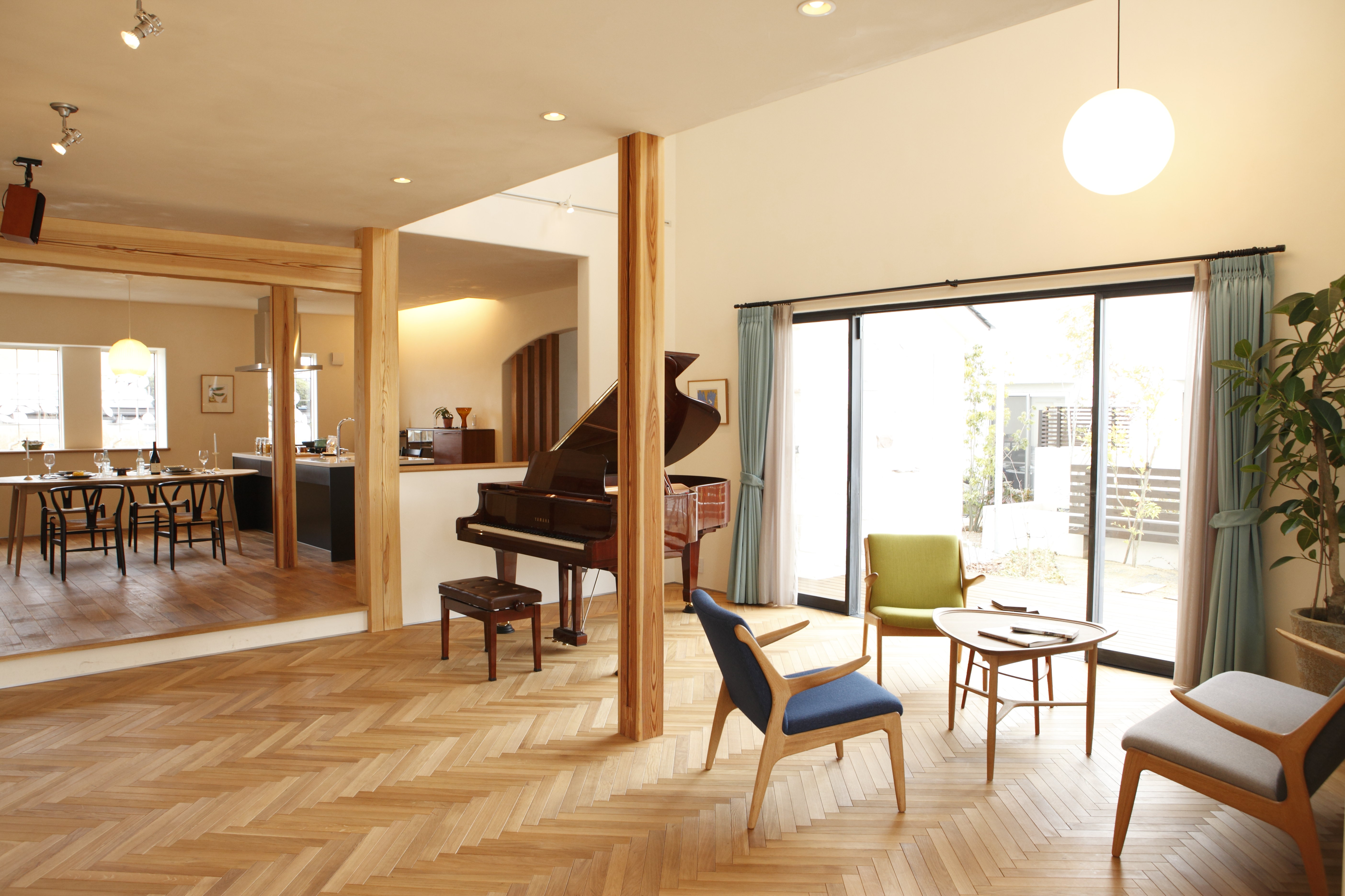ヘリンボーン貼りにされたヨーロピアンオークの床が印象的なピアノホール。カーテンや家具は色づかいにこだわり、照明はシンプルにまとめたコーディネートにしました。